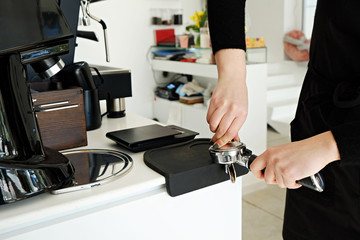 Close up of female barista using modern beautiful coffee machine with vintage style black and chrome texture design to prepare cappuccino. Macro shot of coffee making equipment. Copy space, background