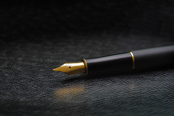 macro of black luxury gold plated fountain pen on dark leather with  copy space