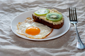 Delicious and healthy breakfast. Fried eggs and kiwi sandwich on white plate