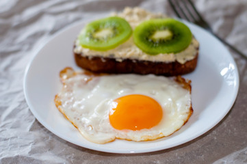 Delicious and healthy breakfast. Fried eggs and kiwi sandwich on white plate
