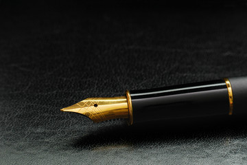 macro of luxury black gold plated fountain pen on black leather with  copy space