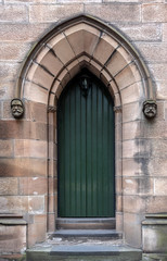 Fototapeta na wymiar Dark green church entrance door recessed into a sandstone pointed archway