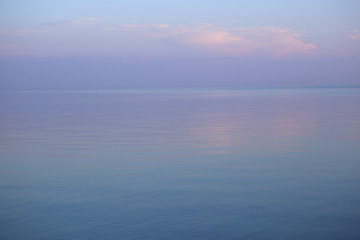 Background of seascape in sunset. Calm sea and purple sky with clouds. 