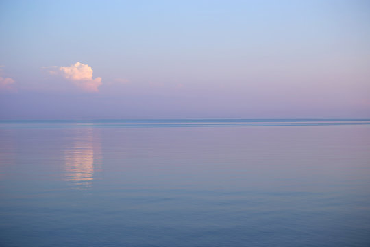 Background of seascape in sunset. Calm sea and purple sky with clouds. 