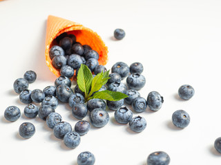 Summer blueberries with a mint leaf in waffle cone isolated on white background. Closeup view
