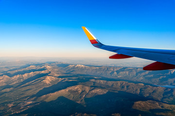 Wing of airplane flying over mountain range