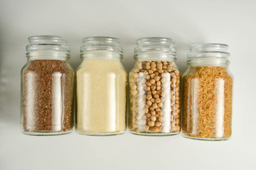 Zero waste concept. Various raw cereals in glass jar. Food storage. Flat lay. White background.