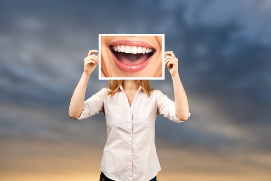 Woman holding picture with big smile. concept photo over dark background