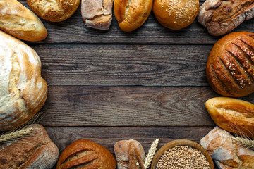 Assortment of baked bread on wooden table background,top view