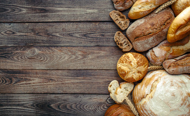 Assortment of baked bread on wooden table background,top view