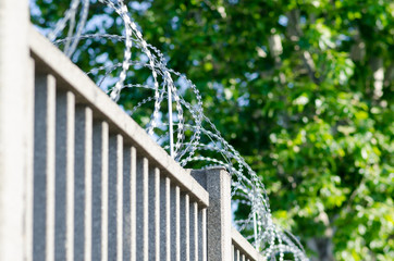 Wall or fence with barbed wire of sharp points that are difficult to climb over.
