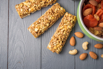Granola cereal flakes with dried fruit, nuts in green bowl on gray wooden table. Top view with copyspace.
