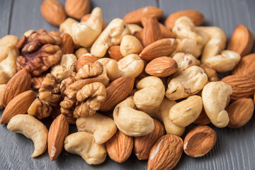 Assortment of nuts on gray wooden table. Cashew, hazelnuts, walnuts, almonds.