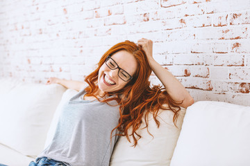 junge glückliche freudige lachende frau mit roten haaren auf der couch portrait