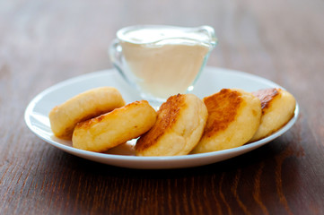 Fried cheese pancakes with sour cream close-up side view. For cafe or restaurant menu design.