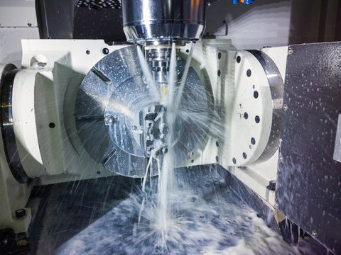 5-axis cnc milling machine at work with coolant under pressure and motion blur of streams..