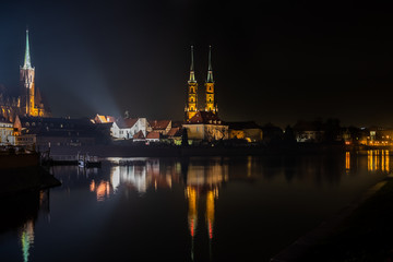 Fototapeta na wymiar Amazing night view of the Cathedral of St. John the Baptist reflected in Oder river. Ostrow Tumski district. Wroclaw. Poland