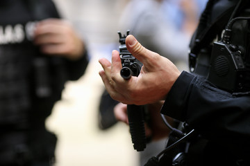 .Details with the hands of a man holding an automatic rifle.