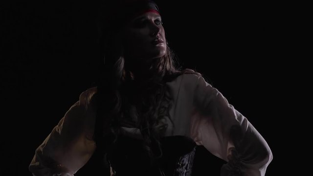 Posing pirate woman in low lighting with her arms on the sides, 4k