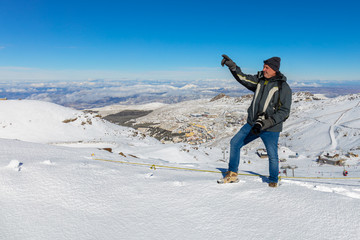 Fototapeta na wymiar About the place Pradollano. A photographer with a camera points his hand towards the summit. The mountains Spanish Sierra Navada near the city of Granada covered in winter snow.