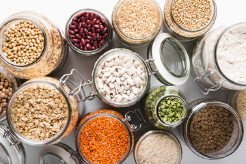 Variety of grains and legumes in glass jars, top view. Zero waste storage concept