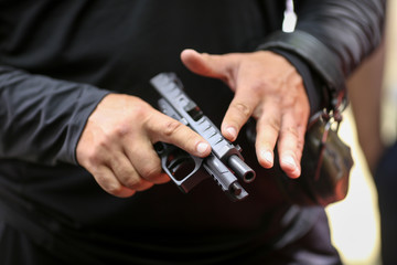 Details with the hands of a man handling a 9mm handgun