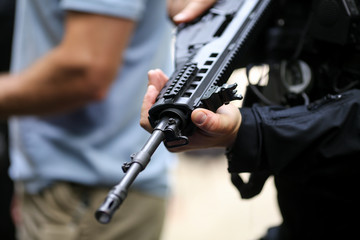 .Details with the hands of a man holding an automatic rifle.