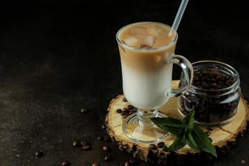 Ice latte or Iced coffee with milk and ice cubes in a glass beaker against a dark background....