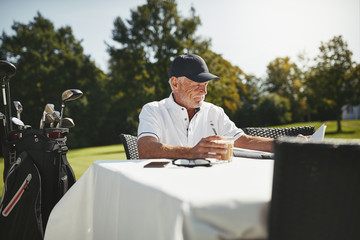 Senior man relaxing at a course restaurant after playing golf