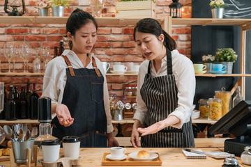 Inexperienced girl barista. angry owner of restaurant scolding new employee behind bar counter. manager dissatisfied with waitress's work of making coffee and baking croissant in modern cafe shop.