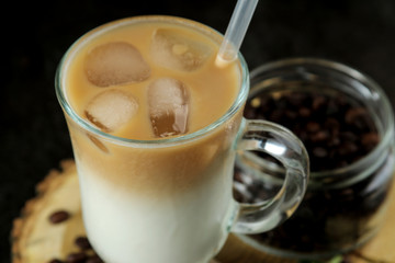 Ice latte or Iced coffee with milk and ice cubes in a glass beaker against a dark background. refreshing drink. summer drink.