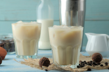 iced coffee with milk and ice cubes in a glass cup on a light blue background. refreshing drink. summer drink.