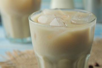 iced coffee with milk and ice cubes in a glass cup on a light blue background. refreshing drink....