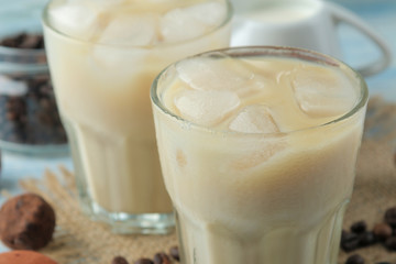 iced coffee with milk and ice cubes in a glass cup on a light blue background. refreshing drink. summer drink.
