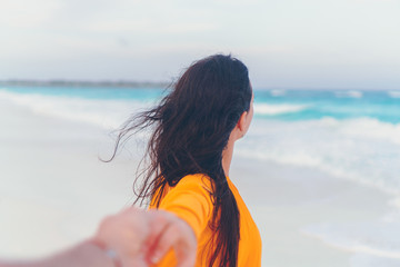 Obraz premium Boyfriend following girlfriend holding hands on white wild beach laughing and smiling