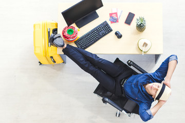 Very relaxed handsome young office worker lying on the chair at his working place after booking tickets for vacation. 