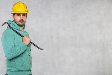 the construction worker holds a work tool in his hands, a crowbar