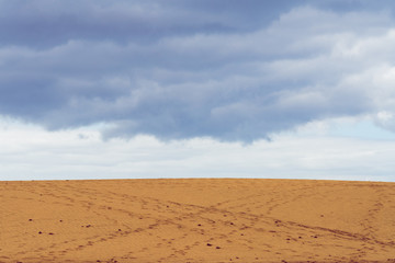 Sand dune with footprints, dark sky in the background