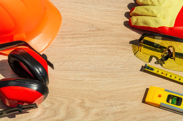 Protective hard hat, headphones, gloves and roulette on wooden background, copy space.