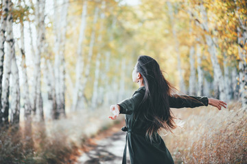 Dreamy beautiful girl with long natural black hair flies on bokeh background of autumn yellow...