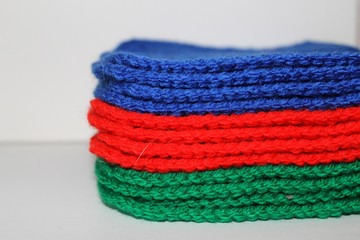 A pile of bright blue, red and green knitted elements on white background. Warm and soft wallpaper, pattern, background