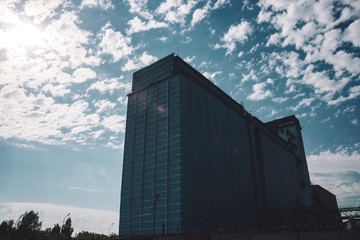 Fototapeta premium Giant multistory production building behind fence with barbed wire. Picturesque old renovated working factory. Aged industrial object. Big manufacturing high-rise building. Industrial area close-up.
