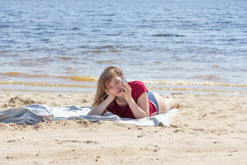 Girl having a rest and taking on mobile phone on summer beach