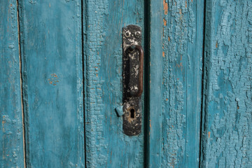 Old wooden door with handle, keyhole. Door with blue cracked paint. Wood texture.