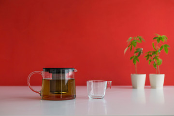 White table with Marijuana plant in pottery. Hot CBD tea in glass and teapot.