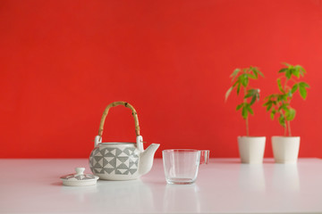 White table with Marijuana plant in pottery. Hot CBD tea in glass and teapot.