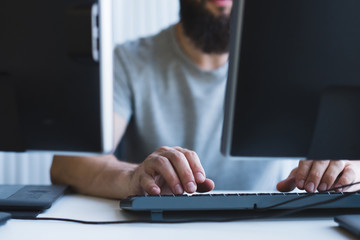 Computer programming. Cropped shot of bearded software developer using two monitors for work at...