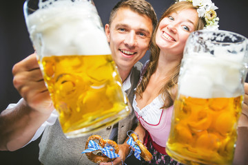  Mann und Frau stoßen mit Maß bier an und lachen auf dem Oktoberfest 