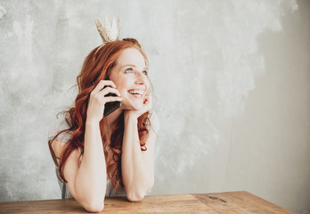 Junge rothaarige Frau mit Krone beim Telefonieren 