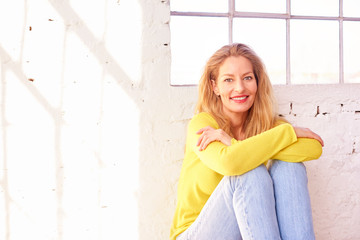 Happy middle aged woman sitting on the floor and relaxing